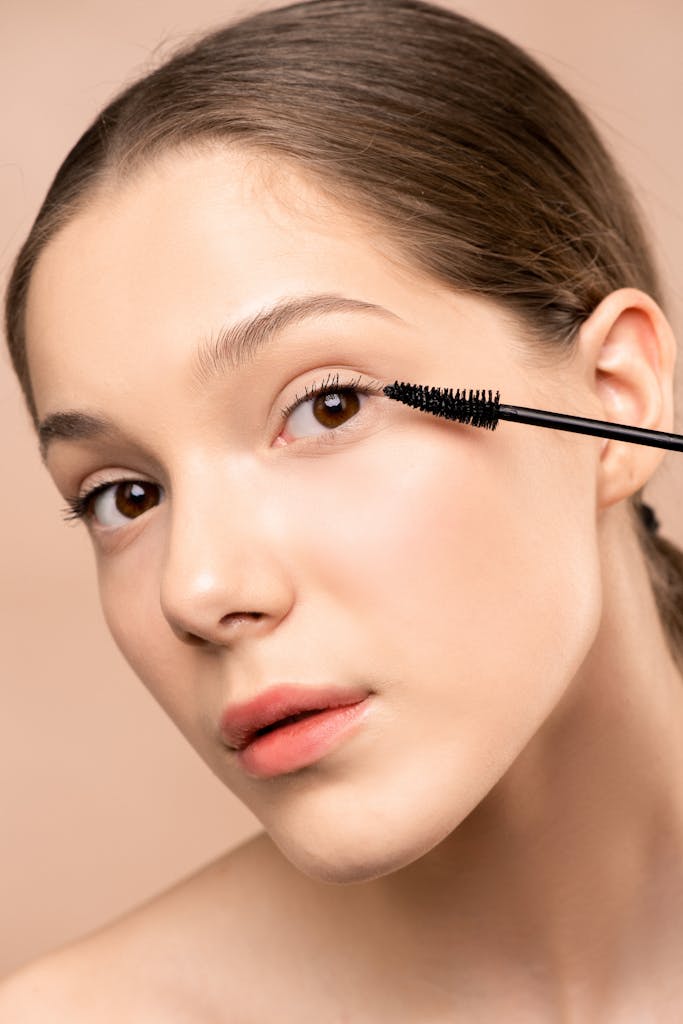 Close-up of a young woman applying mascara to enhance her eyelashes.